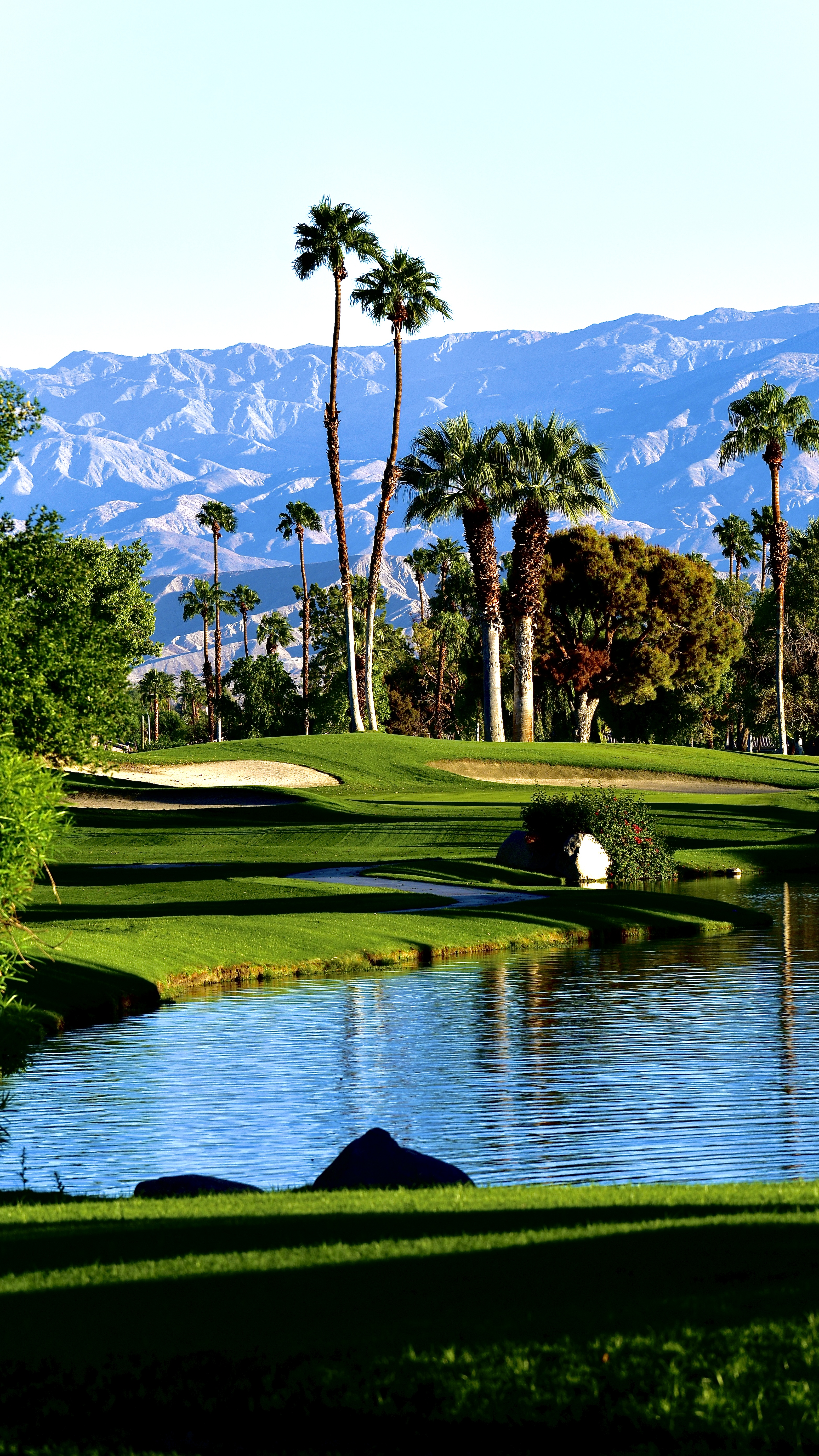 Pond on golf course fairway with trees and bunker